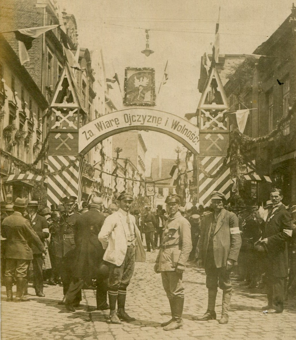 Fotografia przedstawia mężczyzn stojących przed bramą powitalną na ul. Sobieskiego w Rybniku